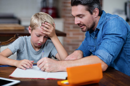 Father helping son with his homework in kitchen at homeの写真素材