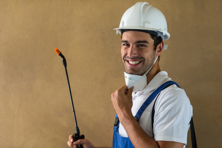 Portrait of happy manual worker with pesticide against wallの写真素材