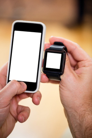 Close-up of mans hand holding smart watch and a mobile phoneの写真素材