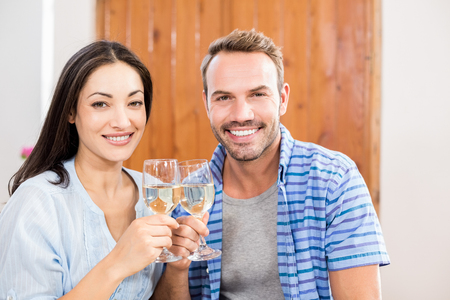 Portrait of young couple toasting wine glass at homeの写真素材