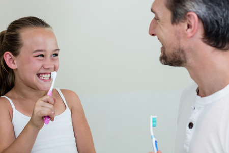 Smiling daughter and father holding a toothbrush in the bathroom at homeの写真素材