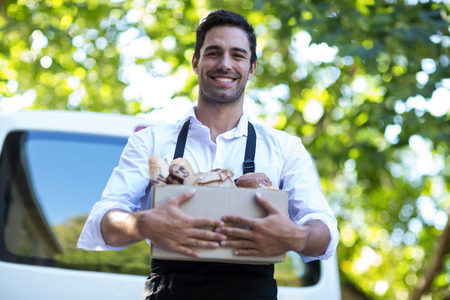 Portrait of happy delivery person carrying package against vanの写真素材