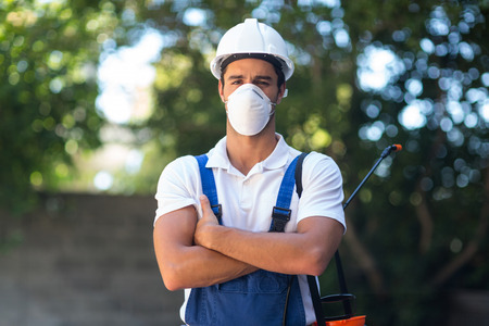 Portrait of confident pesticide worker with arms crossed standing in back yard