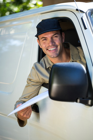 Delivery man with parcel looking through van windowの写真素材