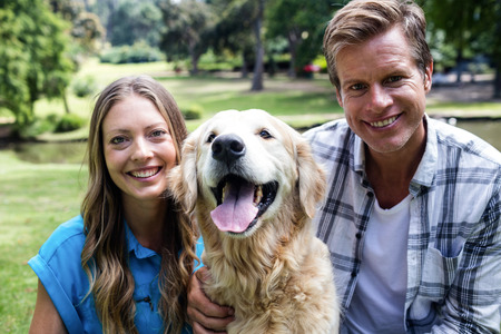 Portrait of a happy couple sitting in the park with their dogの写真素材