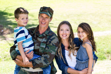 Soldier reunited with his family in the park on a sunny day