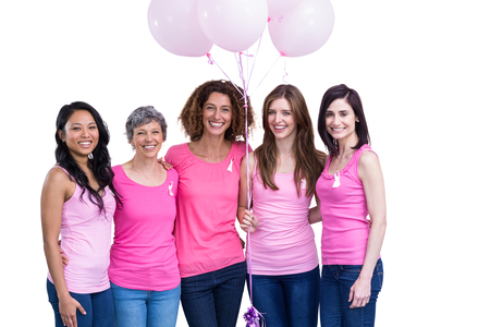 Smiling women in pink outfits posing with balloons for breast cancer awareness on white backgroundの写真素材