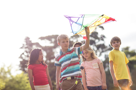 Happy children playing with a kite in the parkの写真素材