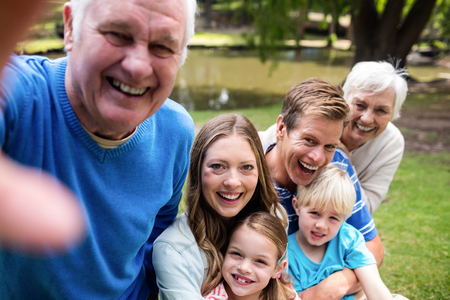 Multi-generation family posing for a selfie in the park on a sunny dayの写真素材