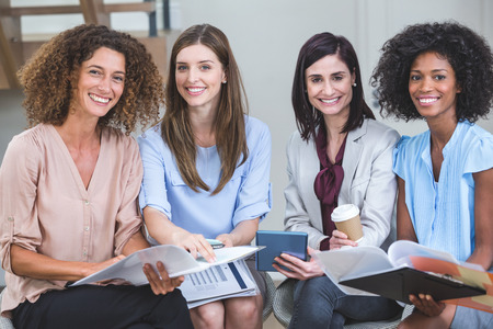 Portrait of female business colleagues sitting together with document in office