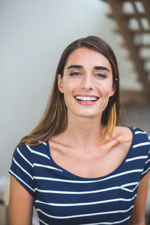 Portrait of beautiful woman smiling in living room at homeの写真素材