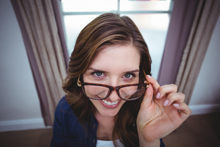 Portrait of beautiful woman holding spectacle and smiling at home