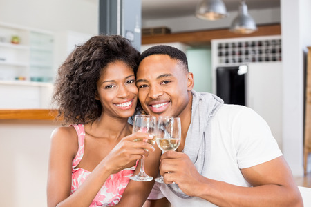 Portrait of young couple toasting wine glasses at homeの写真素材