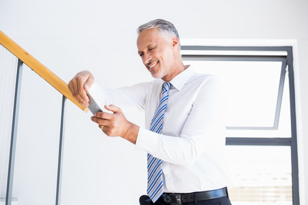Businessman text messaging on mobile phone in the officeの写真素材