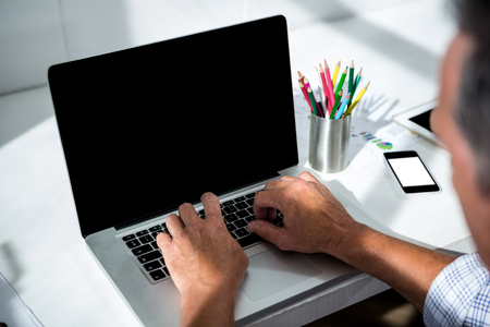 Man in office sitting at desk using laptopの写真素材