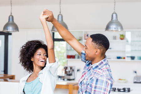 Happy couple dancing in kitchen at homeの写真素材