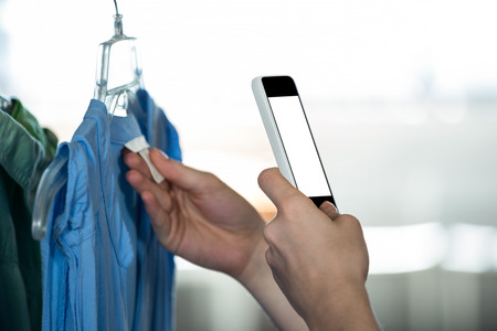 Woman clicking photo tag of garment in apparel shopの写真素材