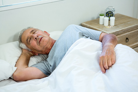 High angle view of senior man sleeping on bed at homeの写真素材