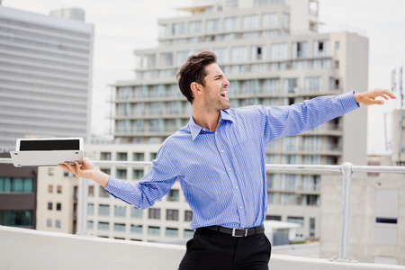 Frustrated businessman throwing laptop on office terraceの写真素材