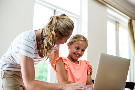 Low angle view of mother with daughter using laptop at tableの写真素材