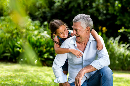 Happy grandfather and grandaughter playing at yardの写真素材