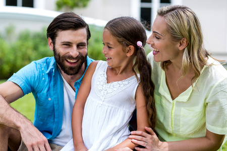 Smiling mother and daughter looking at father sitting in yardの写真素材