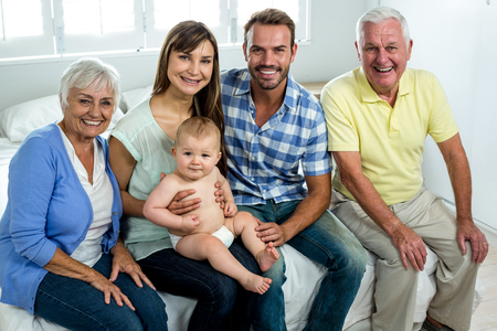 Portrait of happy multi-generation family sitting on bed at home