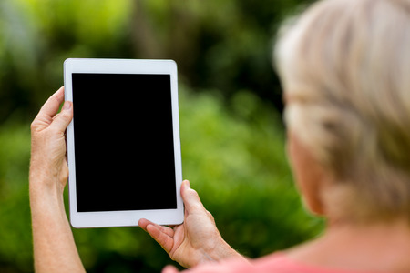 Rear view of woman holding tablet at yardの写真素材