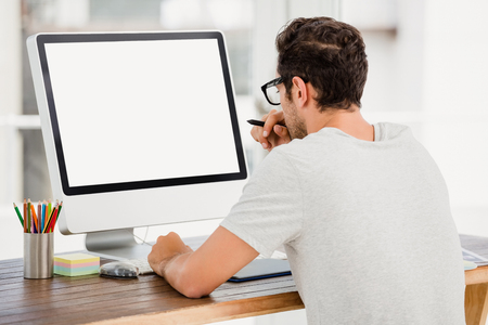 Young man using pen tablet and computer at his desk in the officeの写真素材