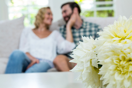 Close-up of dahlias on table against romantic couple at homeの写真素材