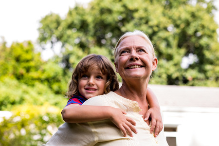 Happy grandmother carrying grandson at yardの写真素材