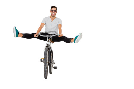 Young man in sunglasses cycling on white backgroundの写真素材