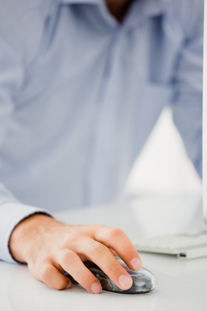 Mid-section of mans hand working on computer in officeの写真素材