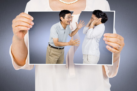 Woman holding a torn photo against grey vignette