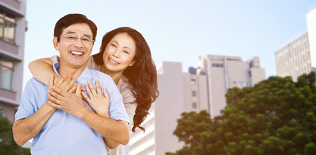 Smiling couple holding each other against low angle view of city buildingsの写真素材