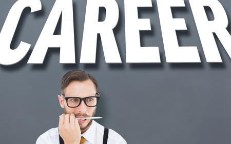 Geeky hipster biting on pencil against grey vignetteの写真素材