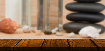 Wooden desk against stack of pebbles with beauty productsの写真素材