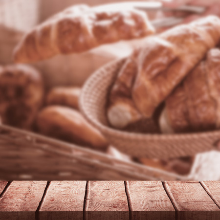 Wooden desk against happy worker holding a basket of croissantの写真素材