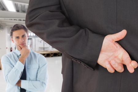 Businessman with fingers crossed against classroomの写真素材