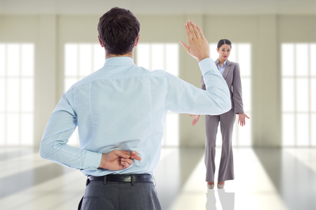 Businessman crossing fingers behind his back against room with windowsの写真素材