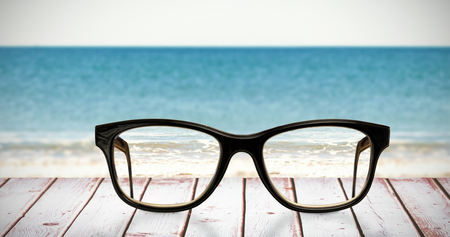 Reading glasses against a picture of a beach