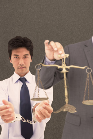 Male lawyer holding scale and gavel against white background against grey backgroundの写真素材
