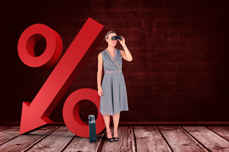 A businesswoman looking through binoculars against a dark wallの写真素材