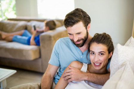 Young couple embracing on sofa at homeの写真素材