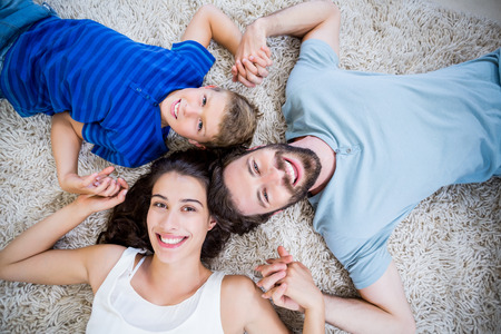 Portrait of parents and son lying on rug at homeの写真素材