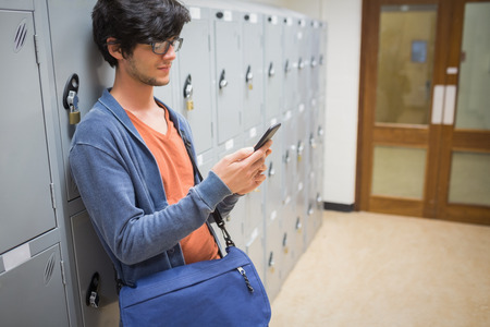 Student standing in locker room and using mobile phone