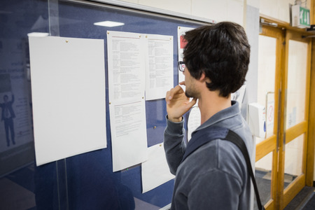Student reading notice board in college