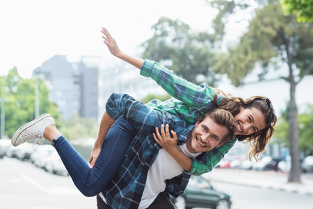 Portrait of man giving piggyback to woman on roadの写真素材