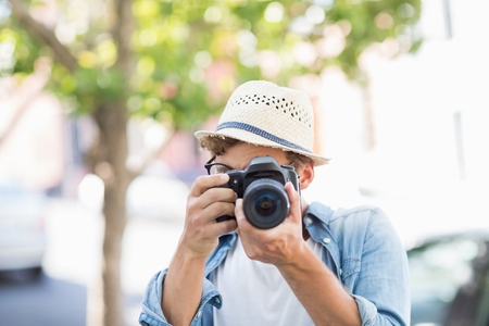 Man wearing hat taking photo outdoorsの写真素材