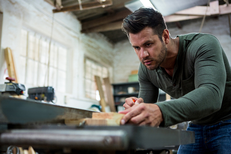 Carpenter working on his craft in a dusty workshopの写真素材